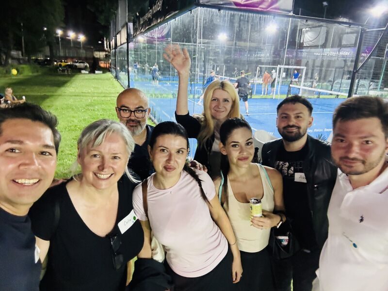 A group of friends smiling together at a night-time Padel and Prosecco event